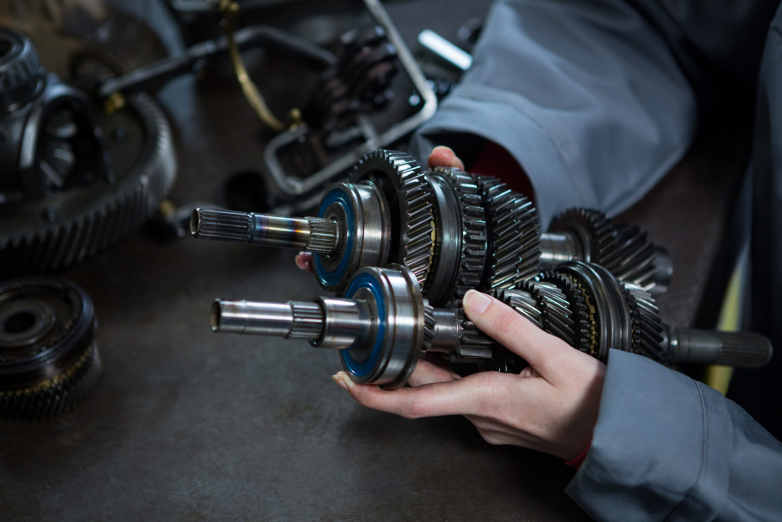 Close-up of female mechanic holding spare parts of car at repair garage